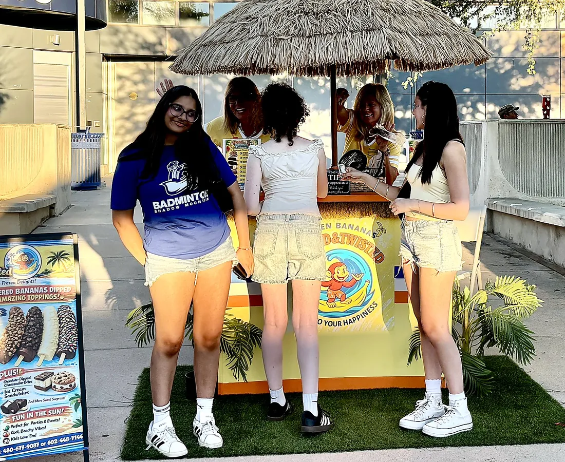 Jules and Elena serving three girls at the Dipped and Twisted tiki cart